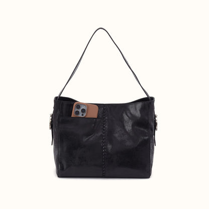 A black leather shoulder bag with a single strap, featuring a front pocket holding a brown leather phone case, set against a plain off-white background.